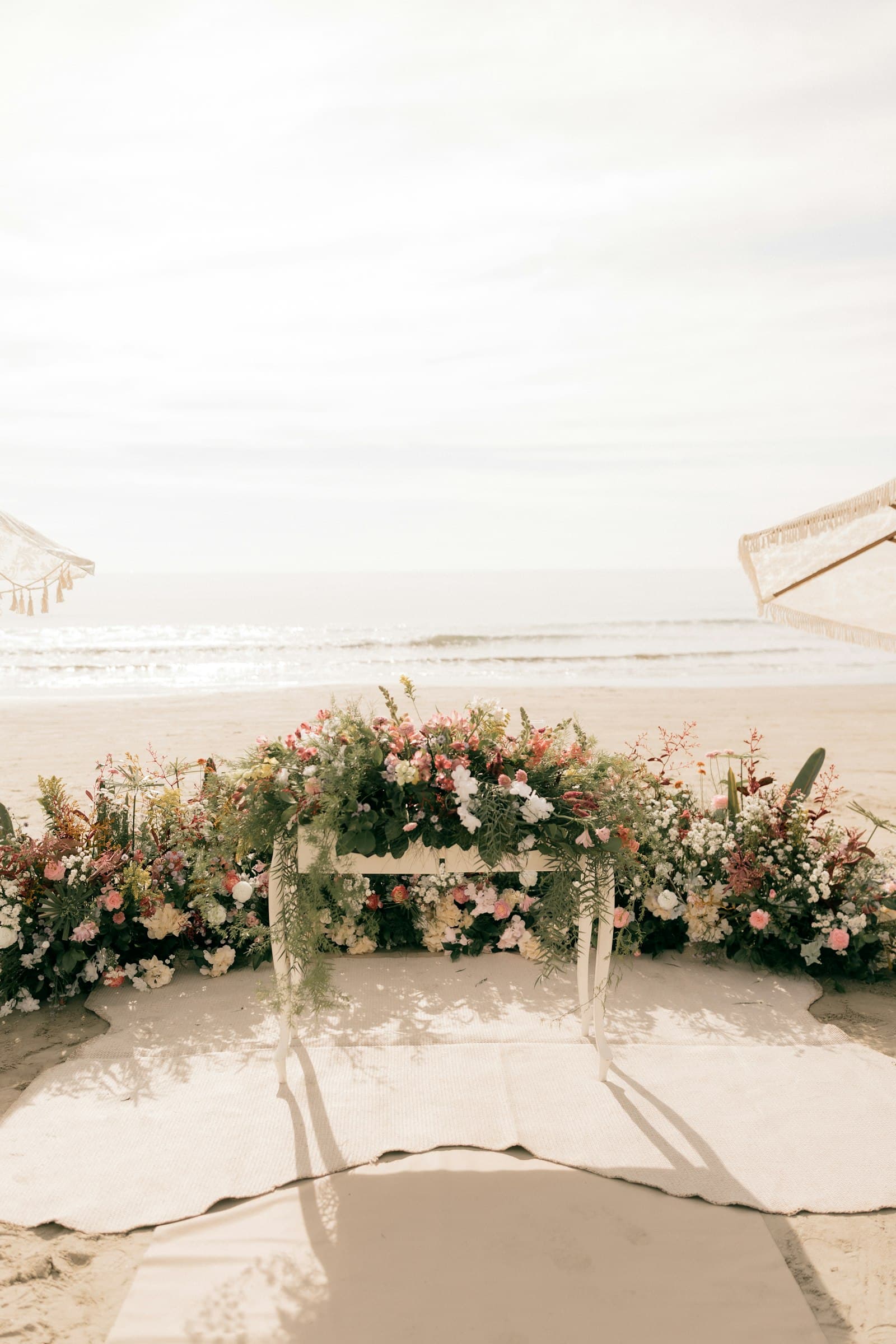 Floral wedding arch on a sandy beach facing the ocean